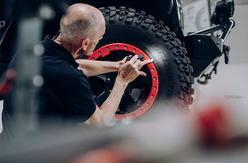 Mechaniker, der an einem Reifen mit rotem Felgenrand arbeitet.