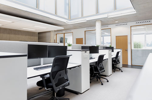 Büroarbeitsplätze mit mehreren Schreibtischen, Monitoren und Bürostühlen in einem modernen Büro.