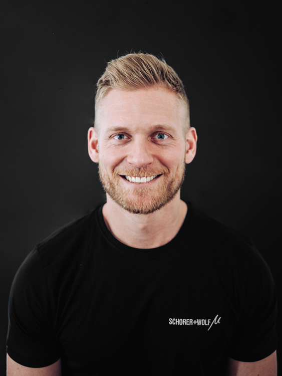 Porträt eines Mannes mit blondem Haar und Bart, der ein schwarzes T-Shirt trägt.